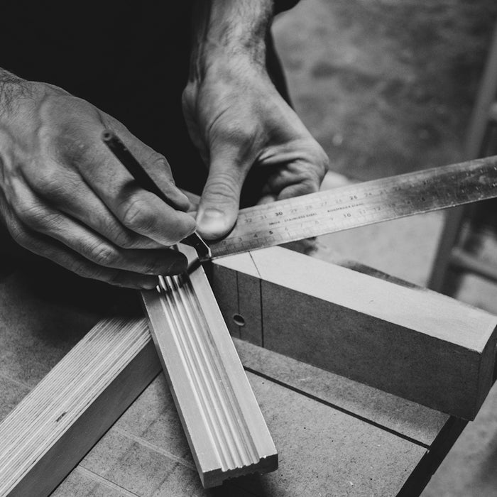 a person cutting a piece of wood with a pair of scissors