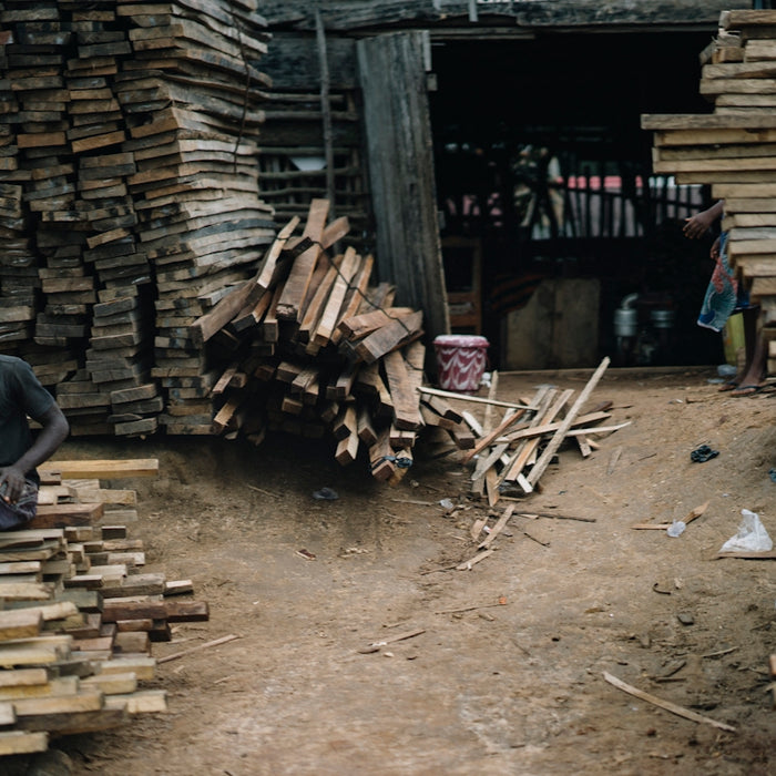 man in black jacket and blue denim jeans sitting on brown wooden bench