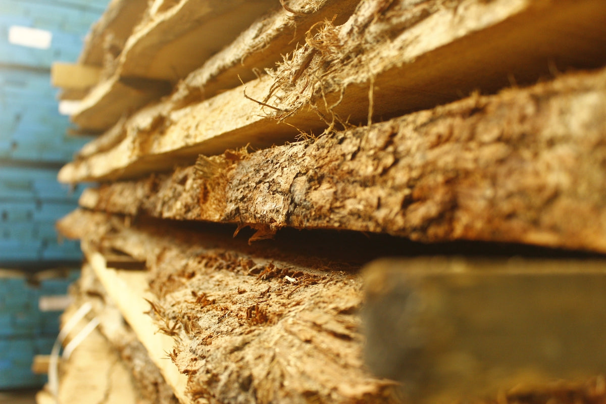 Stack of rough-cut wood planks with bark