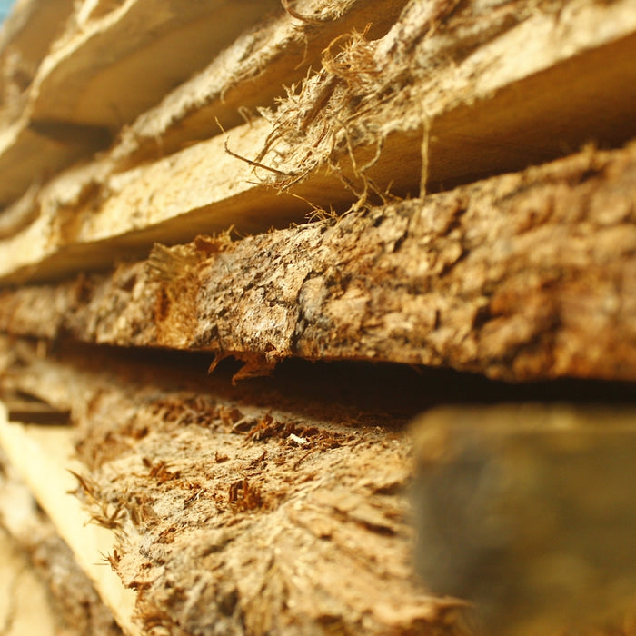 Stack of rough-cut wood planks with bark