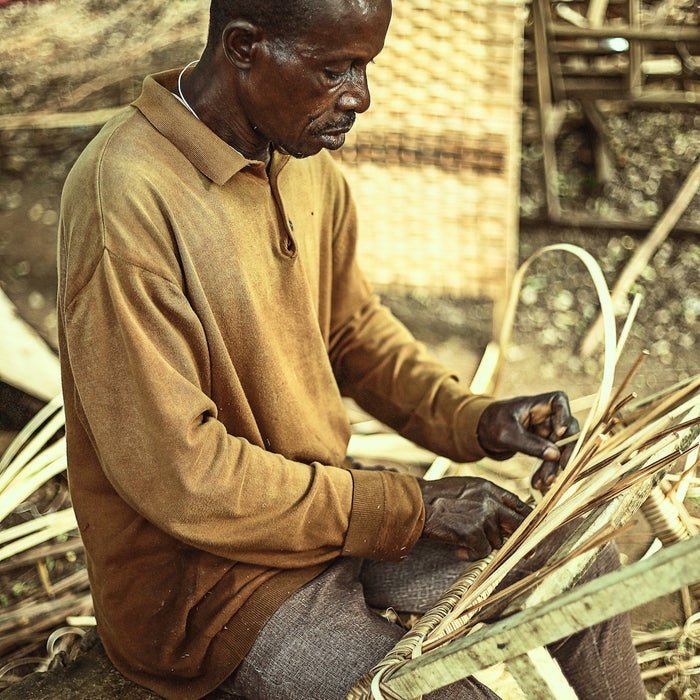 a man sitting on the ground working on a piece of wood
