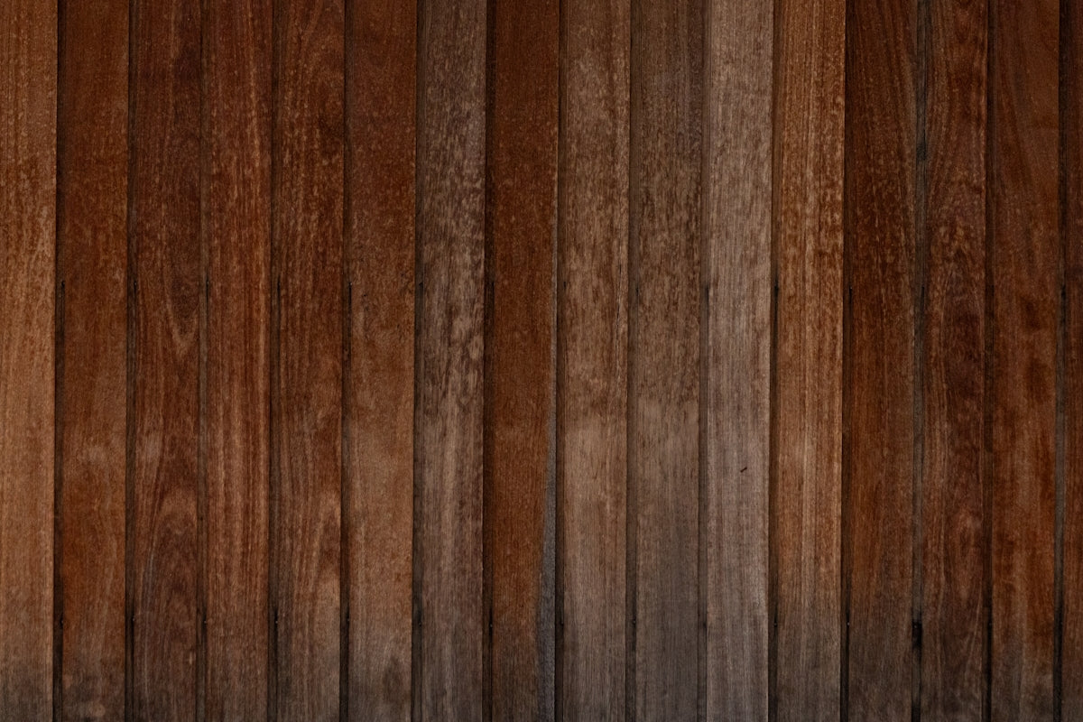 A wooden wall with a black and white cat sitting on top of it