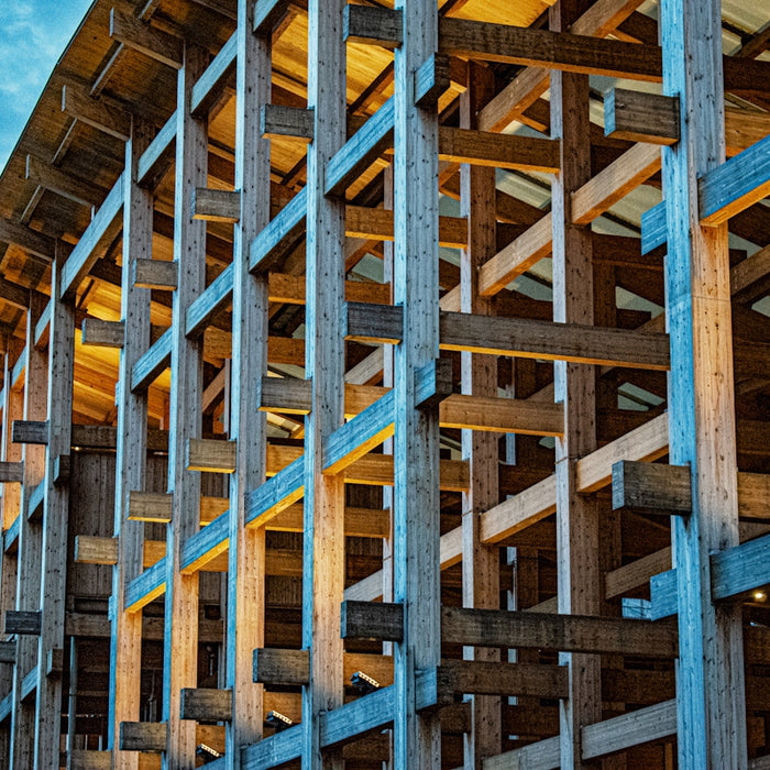 Wooden beams form a large abstract structure against sky